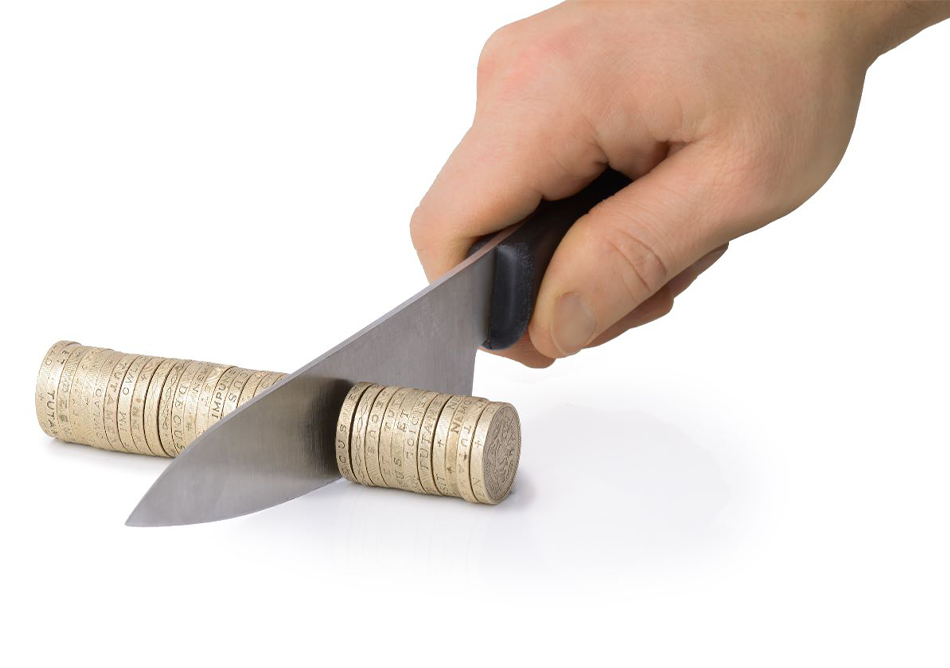 Messer schneidet Geldstapel durch als Symbol für Kürzung der Dividende